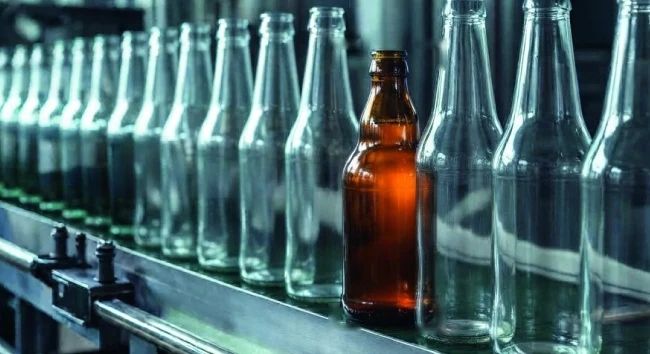 Braune Fremdflasche zwischen klaren Glasflaschen auf dem Förderband, markiert